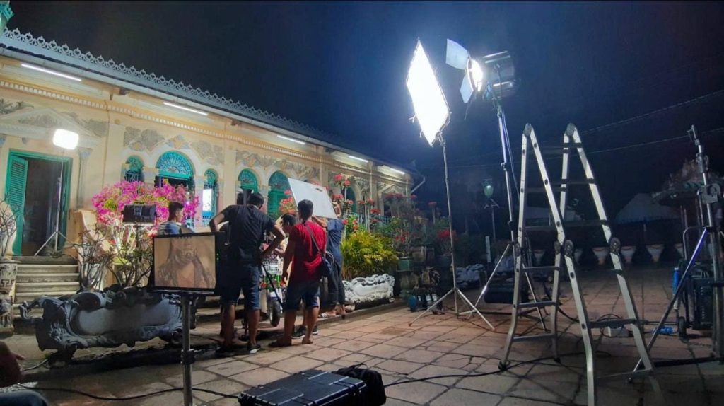 Ekip quay phim thiết lập hệ thống đèn và camera cho cảnh quay ngoài sân vào ban đêm.