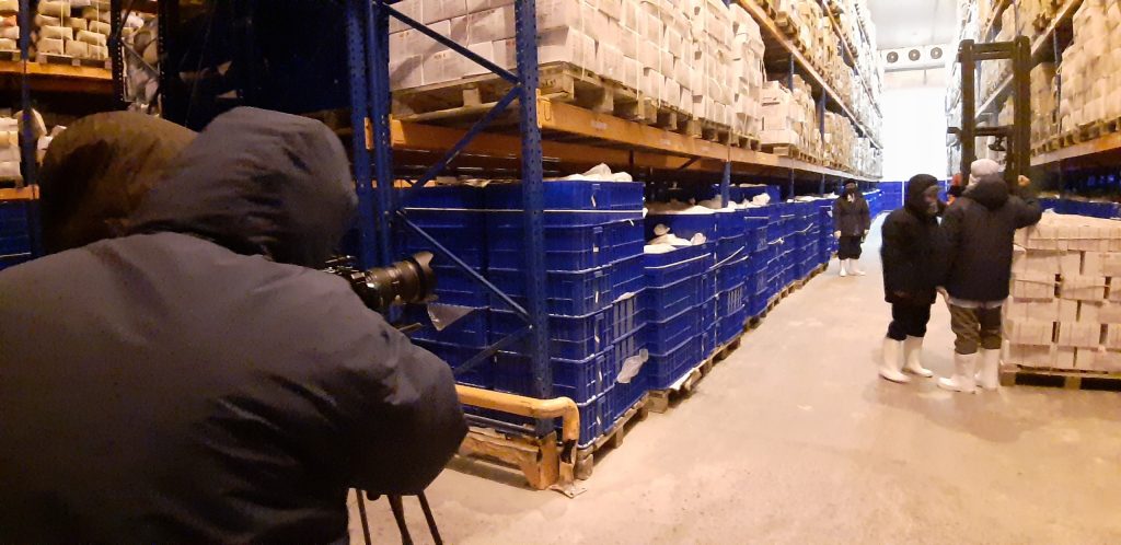 Cameraman tác nghiệp trong kho lạnh khi quay video tại môi trường sản xuất công nghiệp.